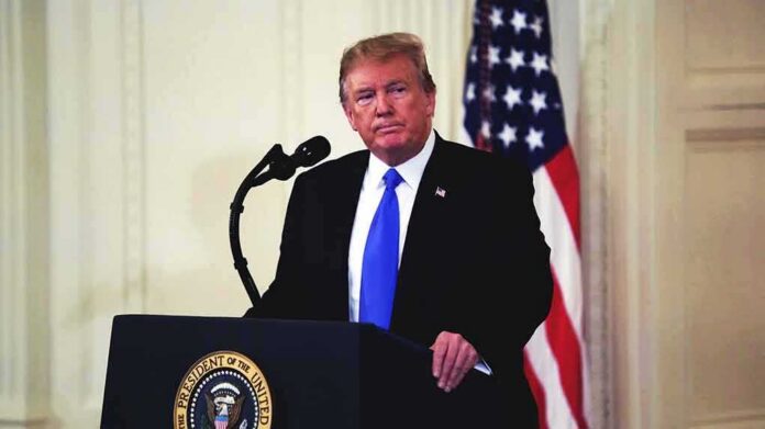 man at podium with microphone and US flag