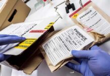 Gloved hands handling labeled evidence bags and boxes