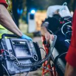 A Touchdown, Then An Unthinkable Sideline Emergency Paramedic with defibrillator beside patient on stretcher