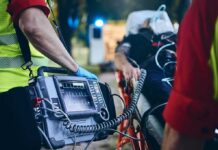 Paramedic with defibrillator beside patient on stretcher