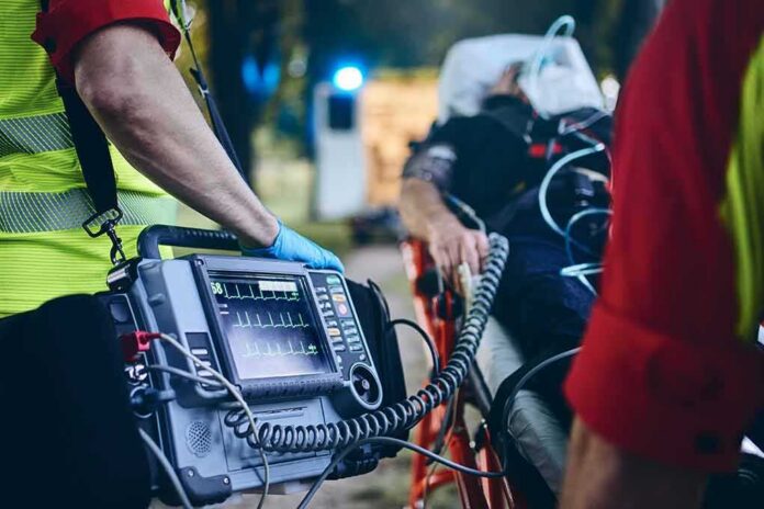 Paramedic with defibrillator beside patient on stretcher
