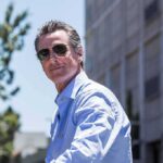 man in sunglasses wearing a light blue shirt outdoors