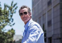 man in sunglasses wearing a light blue shirt outdoors