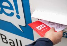 Hand inserting mail-in ballot envelope into drop box