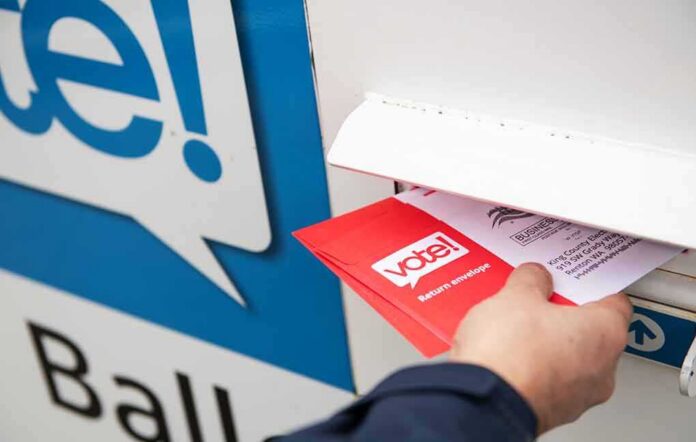 Hand inserting mail-in ballot envelope into drop box