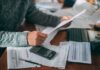 Person reviewing bills with calculator at cluttered desk