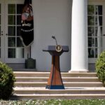 Friendly Fire Hits Maine Democrats Podium with presidential seal in a garden colonnade
