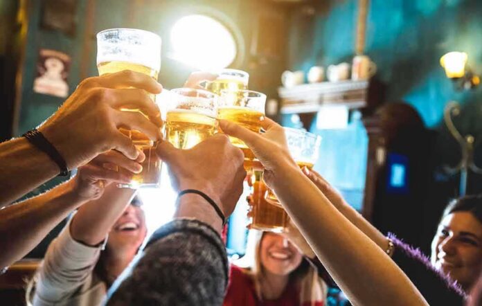 shutterstock_1085215253 group toasting with beer glasses in a pub