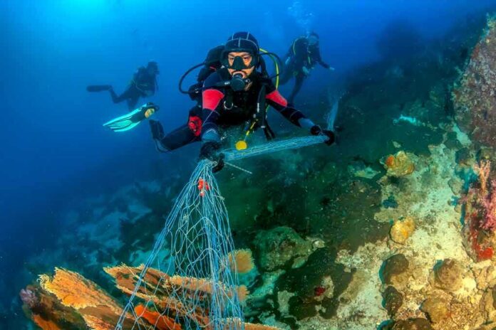 shutterstock_1159616743 Scuba diver removing fishing net from coral reef