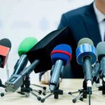 Is Piker Funded by a Chinese Tycoon? Gaps Remain microphones clustered on a table at a press conference