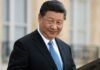 Xi Jinping in a dark suit with a blue tie, smiling outdoors