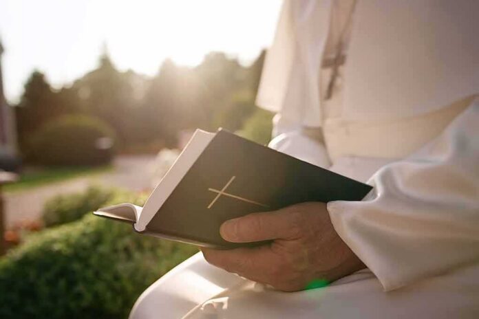 shutterstock_1534724576 Person in white robe holding a Bible outdoors