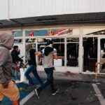Tiny Victim, Big City Violence — Bronx Outrage people moving past a storefront with broken windows