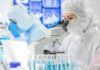 Scientist in protective suit using a microscope