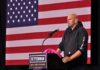 man at podium speaking with US flag backdrop