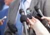 FBI Affidavit Targets Journalist – Espionage? Microphones held toward a person in a suit