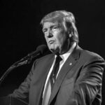 Inflation Panic Flattens Approval man in suit speaking at a microphone