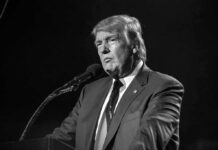 man in suit speaking at a microphone