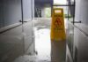 Yellow wet floor caution sign on a shiny wet hallway