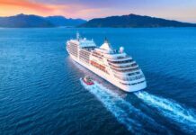 Cruise ship sailing at sunset near mountainous coastline