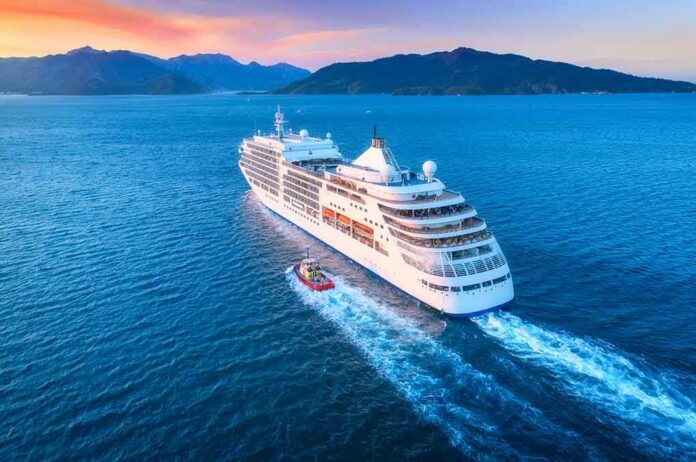shutterstock_1070844110 Cruise ship sailing at sunset near mountainous coastline