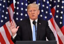 Donald Trump speaking at a podium with American flags behind him