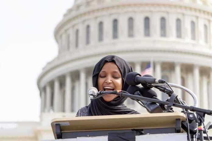 Woman in hijab speaking at podium with microphones