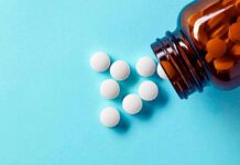 White tablets spilling from brown pill bottle