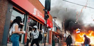 Street protest with fire and smoke outside a bank