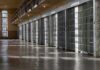 Row of prison cells with metal bars along an empty corridor