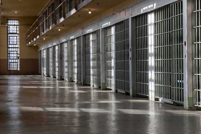shutterstock_1628186173-2 Row of prison cells with metal bars along an empty corridor