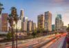 city skyline with palm trees and busy freeway at dusk