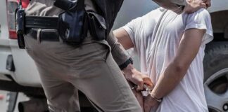 police officer handcuffing a person beside a vehicle