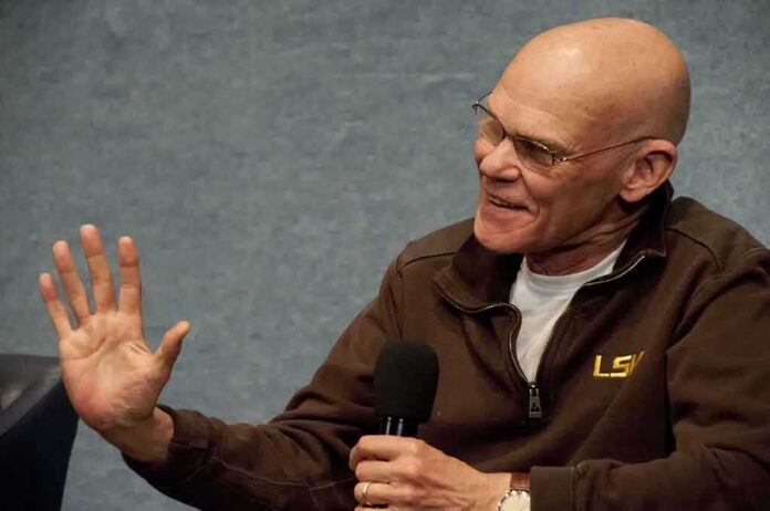 shutterstock_171951746 James Carville speaking into a handheld microphone, gesturing with his left hand