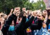 Crowd of protesters with raised fists wearing masks