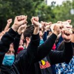 Crowd of protesters with raised fists wearing masks