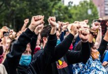 Crowd of protesters with raised fists wearing masks