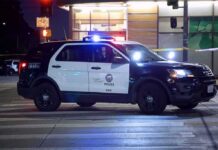 Police SUV blocks an intersection at night with lights flashing