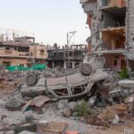 Overturned car amid rubble and heavily damaged buildings