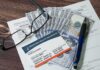 Medicare card on paperwork with cash, glasses, and a pen