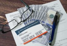 Medicare card on paperwork with cash, glasses, and a pen
