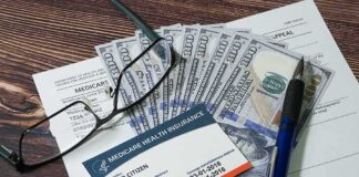 Medicare card on paperwork with cash, glasses, and a pen