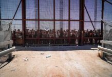 2.7-to-1 Drop Sparks Right-Wing Victory Lap Crowd stands behind tall metal fence at border crossing