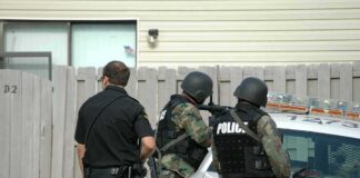 police officers in tactical gear beside patrol car