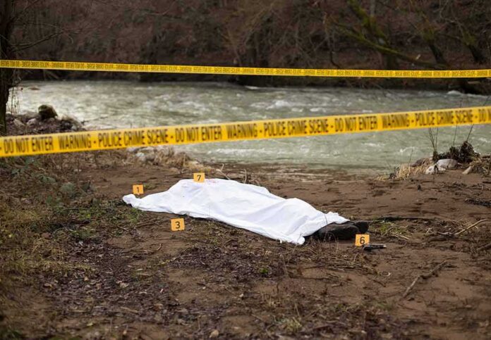 shutterstock_792627442 covered body at riverside crime scene with evidence markers
